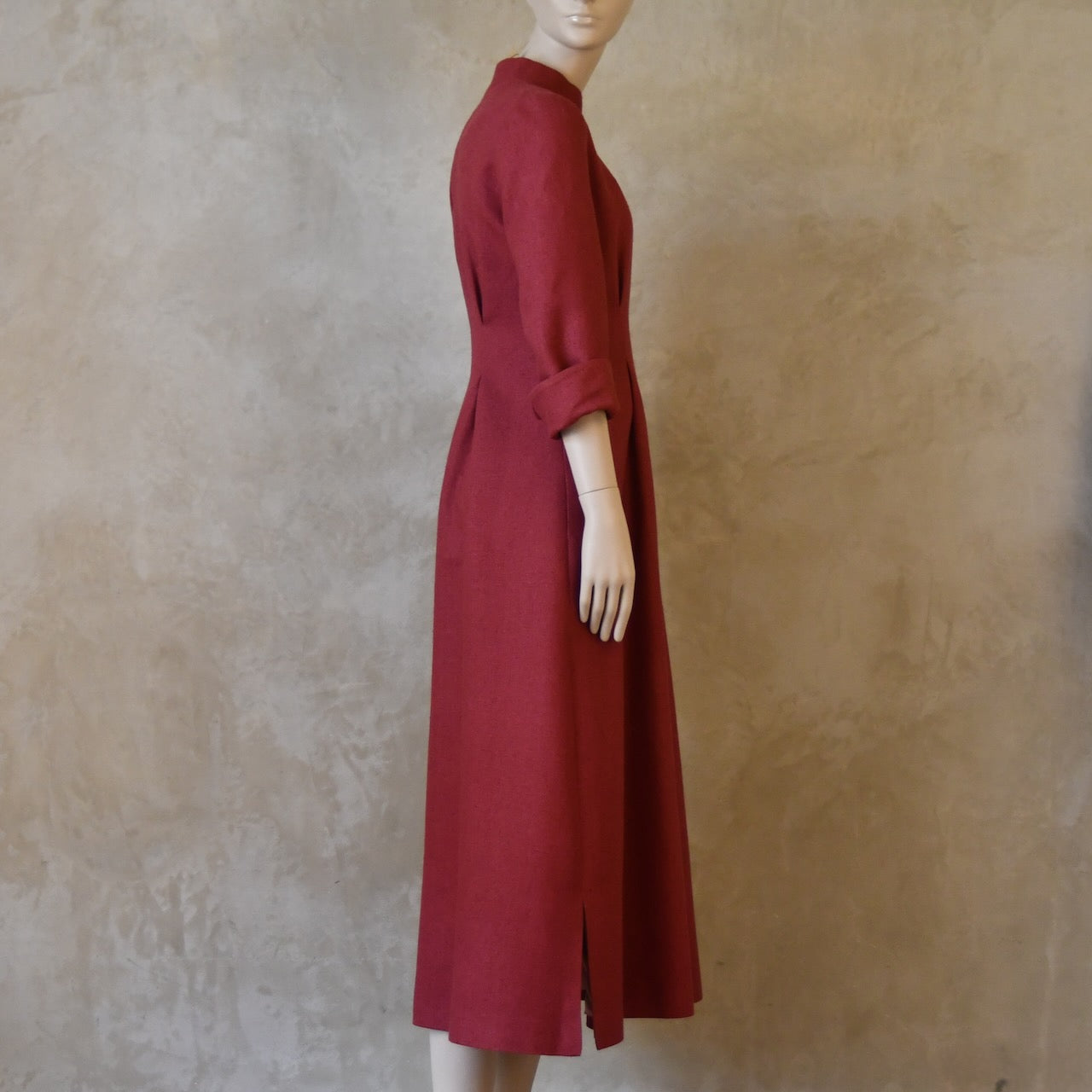 Full on side shot of Side Angled shot of waisted silk dress. Handmade in London this pink dress has a nipped in waist, mid length sleeves, turn back cuffs and gently flattering inverted darts at the rear. Slits to the side and an open neckline with a Nehru collar. 