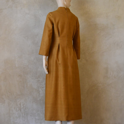 Turning back shot of Tan coloured tailored formal wear silk dress. Three quarter length sleeves, fully lined in silk with gathering darts at front and rear creating flattering hourglass shape. Handmade in London.