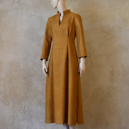 Turning shot of Tan coloured tailored formal wear silk dress. Three quarter length sleeves, fully lined in silk with gathering darts at front and rear creating flattering hourglass shape. Handmade in London.