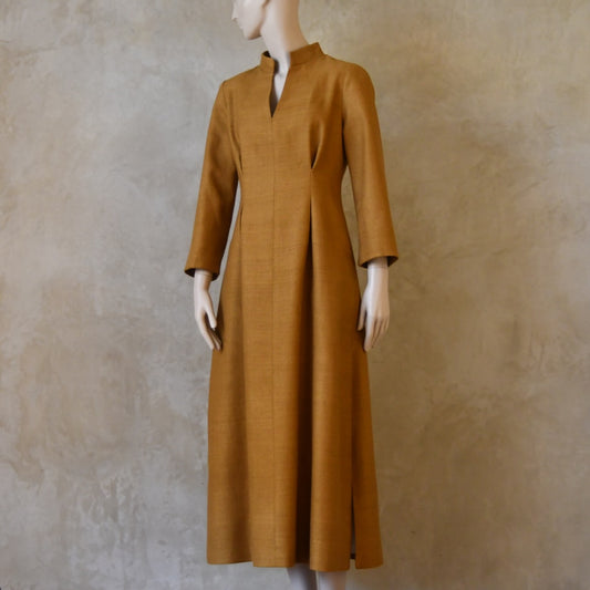Turning shot of Tan coloured tailored formal wear silk dress. Three quarter length sleeves, fully lined in silk with gathering darts at front and rear creating flattering hourglass shape. Handmade in London.