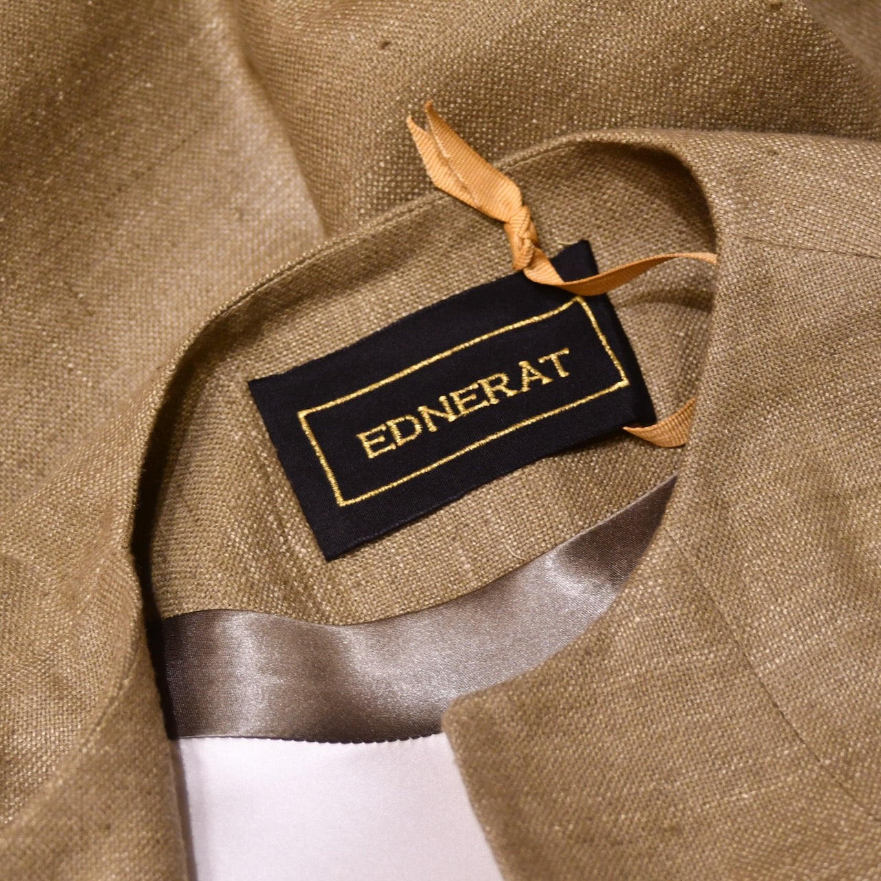 Neck detail showing silk lining, satin trim and embroidered label on Pure Silk formal summer coat in size 18. With a nipped in waist detail this coat is superbly elegant and perfect for wearing at formal spring-summer occasions. Handmade in London and lined in pure silk.