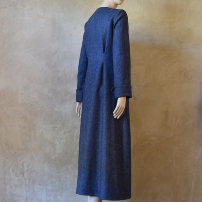 Angled Side view of Side Angled view of Bespoke Hourglass Tweed Coat, Handmade in London. Denim Blue herringbone tweed dress coat, ideal for winter weddings, race fixtures and other formalwear occasions. Fully lined in pure silk, with optional Nehru collar, fold back cuffs and self-fabric wrap around belt.
Longer or calf length coat.