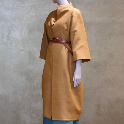 Full length Belted shot of the EdNerat Silk Cocoon Coat in Tan, worn over the Skirted Hourglass Dress in Emerald Green. A mid length summer coat, perfect for throwing over the most relaxed of outfits. Handmade in London.