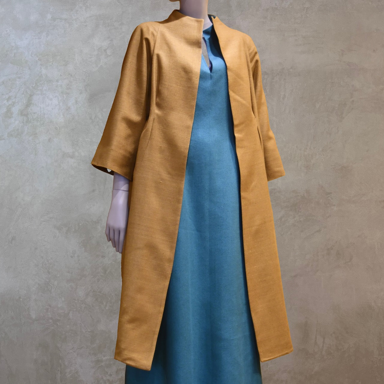 Full length shot of the EdNerat Silk Cocoon Coat in Tan, worn over the Skirted Hourglass Dress in Emerald Green. A mid length summer coat, perfect for throwing over the most relaxed of outfits. Handmade in London.