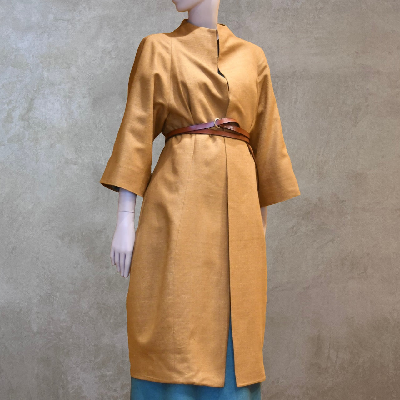 Straight on Belted Shot of the EdNerat Silk Cocoon Coat in Tan, worn over the Skirted Hourglass Dress in Emerald Green. A mid length summer coat, perfect for throwing over the most relaxed of outfits. Handmade in London.