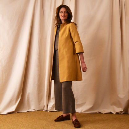 Bespoke Trapeze Swing Coat in Golden Yellow Brocade. Spring Summer MidLength Swing Coat with slight vintage feel and flattering seaming details to front and rear. Front view shown over contrast linen pant suit.