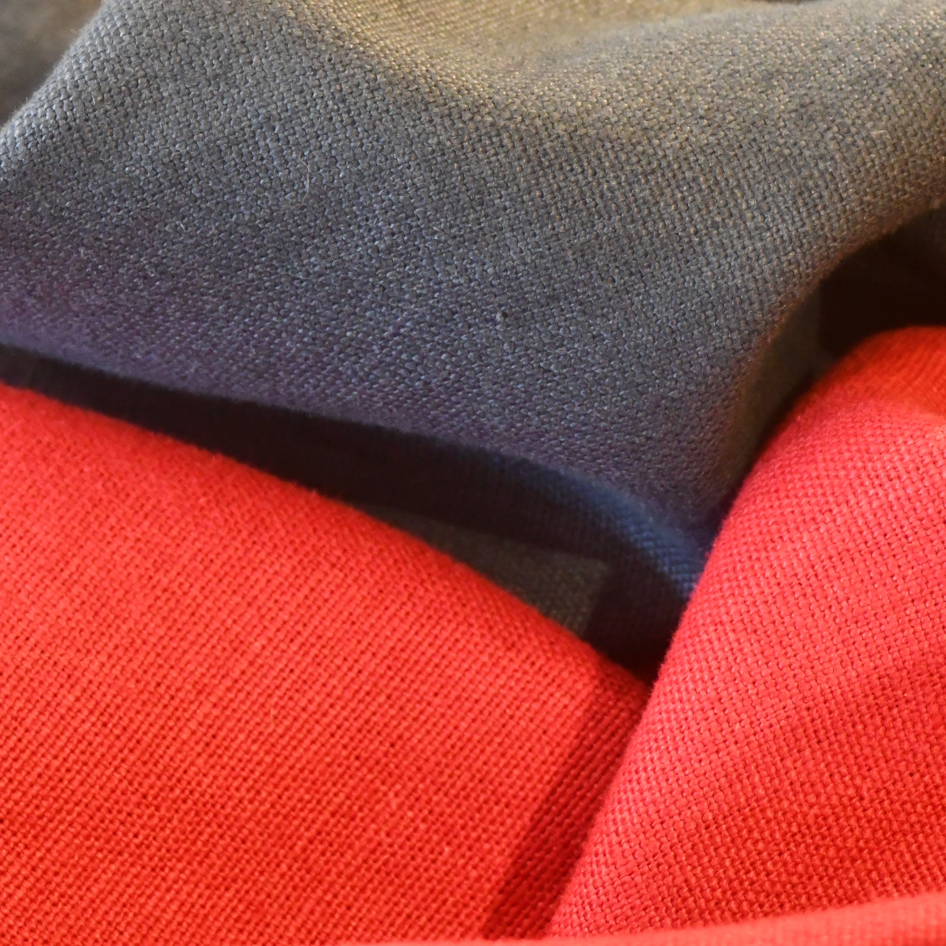 Close-up of British-made red and dark blue fabric pieces layered together, highlighting the texture and weave of the material.