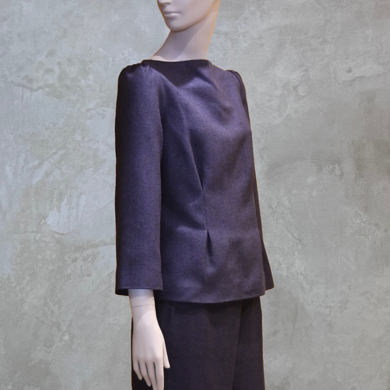 A Tailored Boat Neck Blouse in DarkBlue-Black Silk Matka with a matching skirt, posed sideways. A refined ensemble defined by elegant lines. Handmade in Britain. 