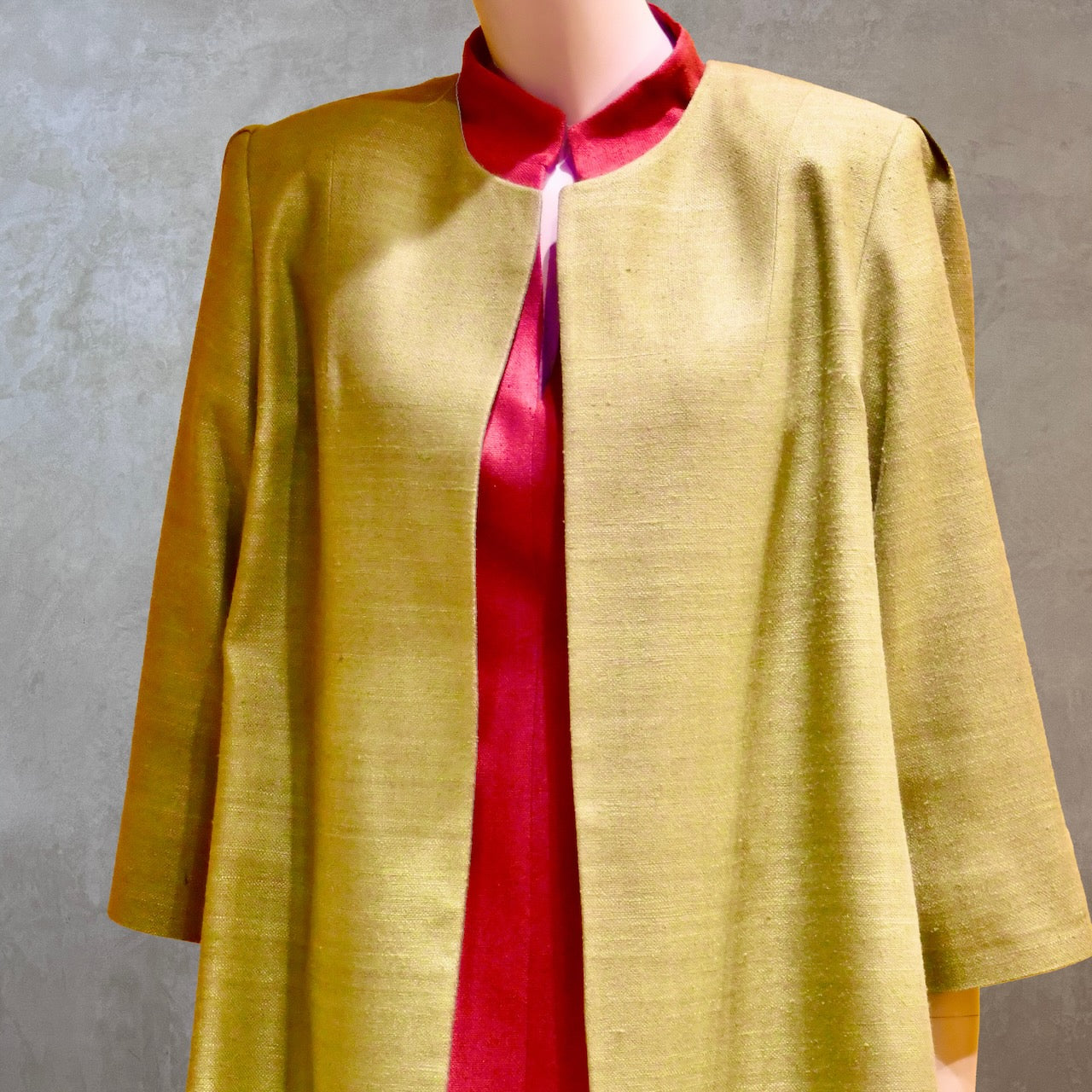 Close up view of Silk car coat in lime green. This is a Mid length coat with shoulder detail in an easy to wear trapeze shape. Fully lined in silk and made by hand in London.