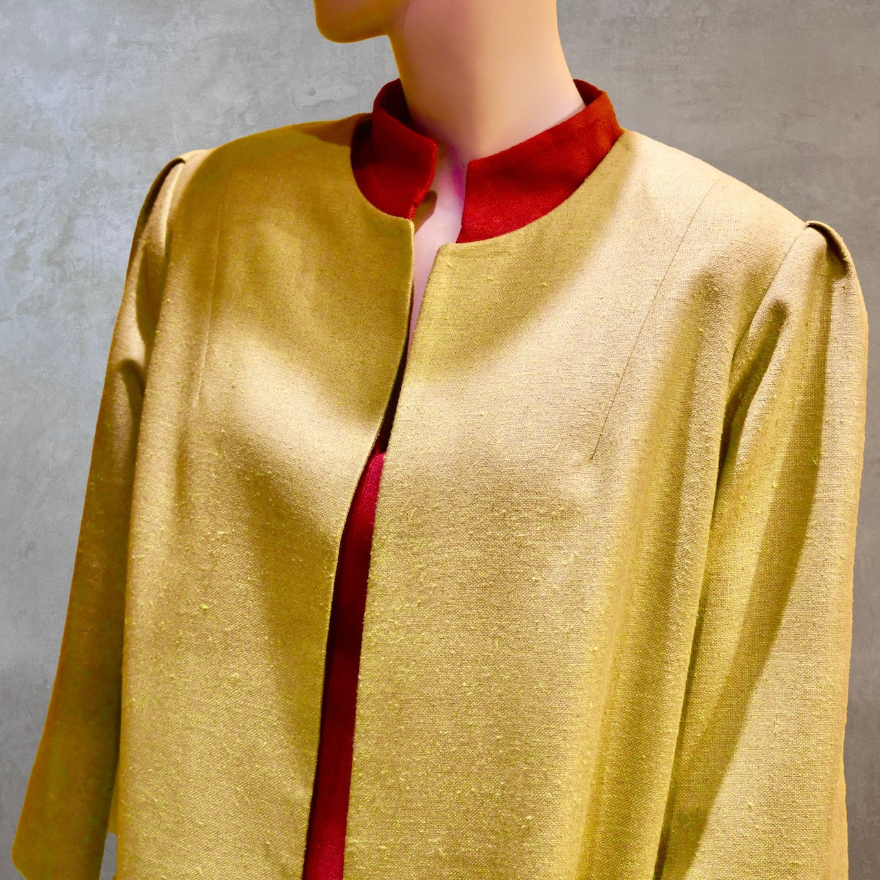 Shoulder detail of Silk car coat in lime green. This is a Mid length coat with shoulder detail in an easy to wear trapeze shape. Fully lined in silk and made by hand in London.