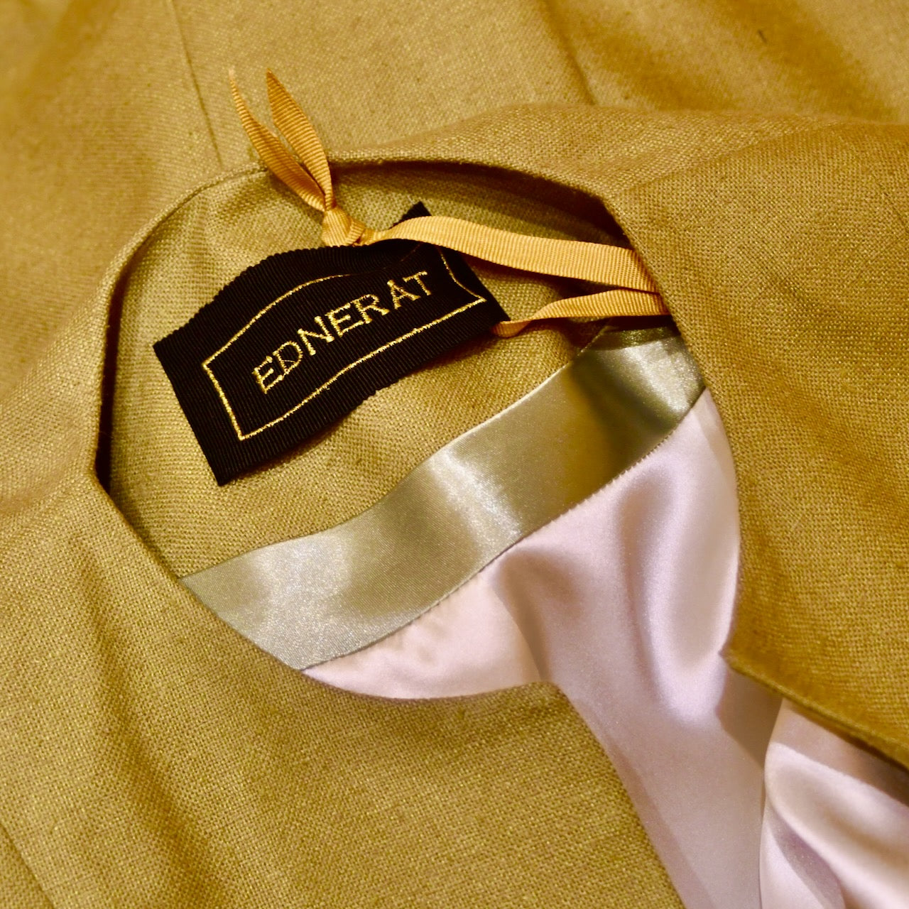 Neck detail showing lining of Silk car coat in lime green. This is a Mid length coat with shoulder detail in an easy to wear trapeze shape. Fully lined in silk and made by hand in London.