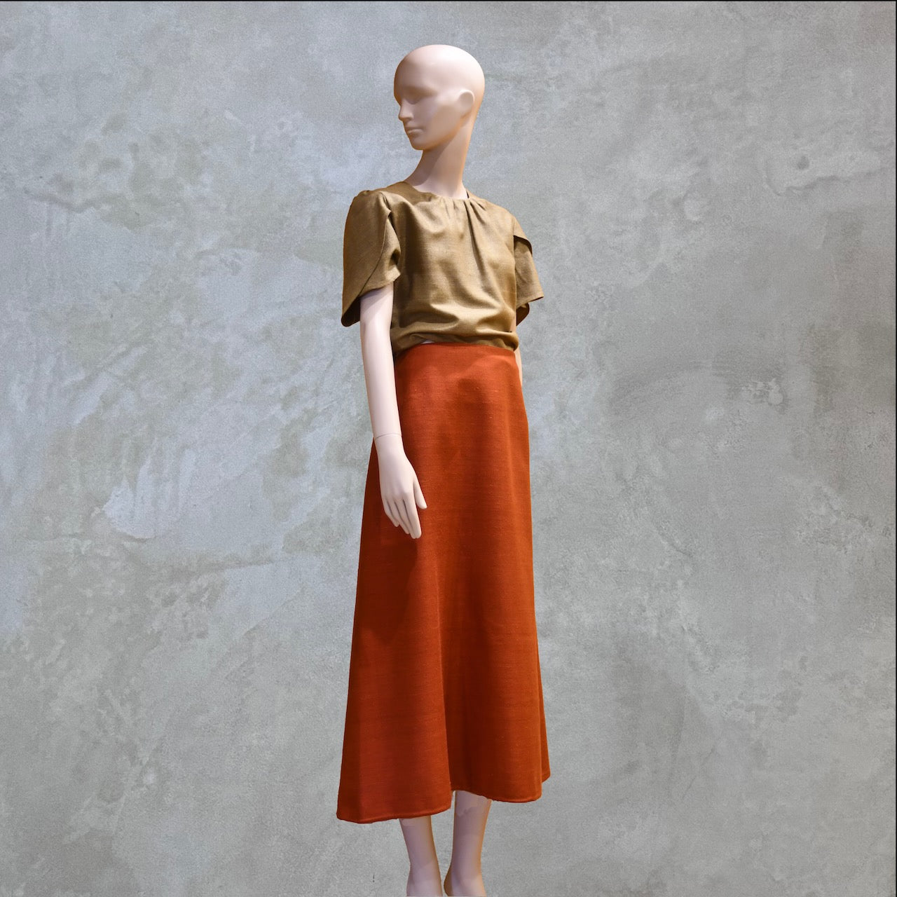 A Khaki tulip-sleeve blouse paired with a terracotta silk skirt. Handmade in Britain.