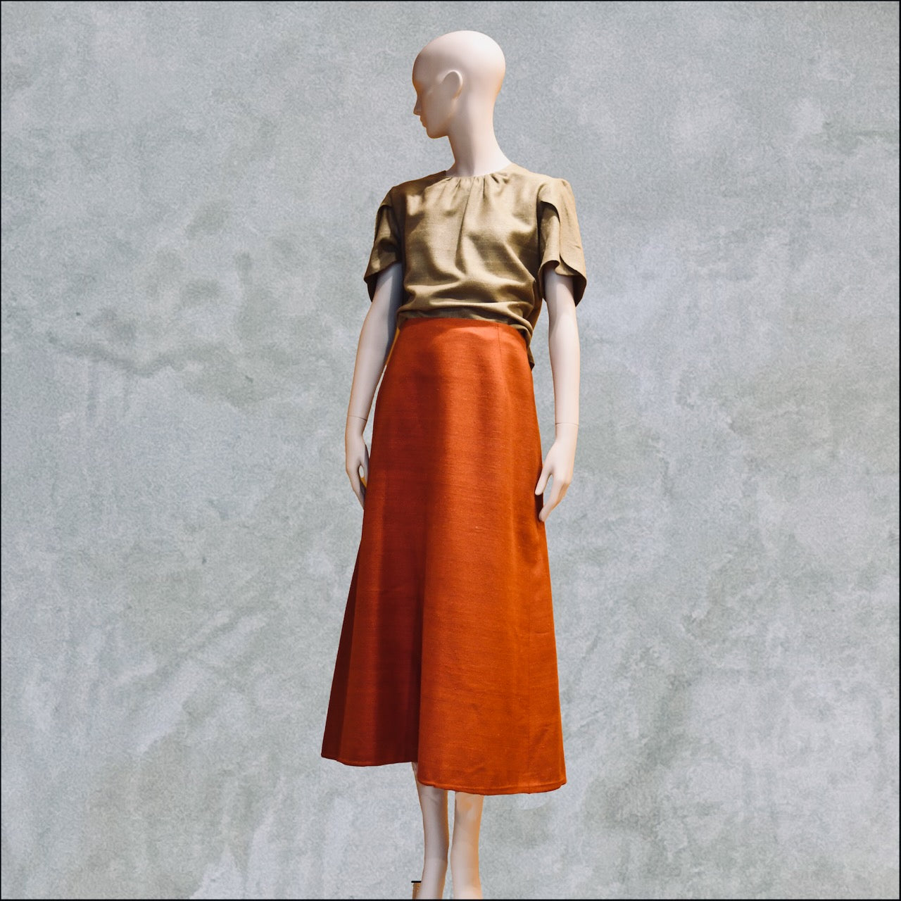 A Tulip Sleeve Blouse in Khaki Silk Matka shown with a terracotta orange silk A-Line Skirt. Handmade in Britain. 
