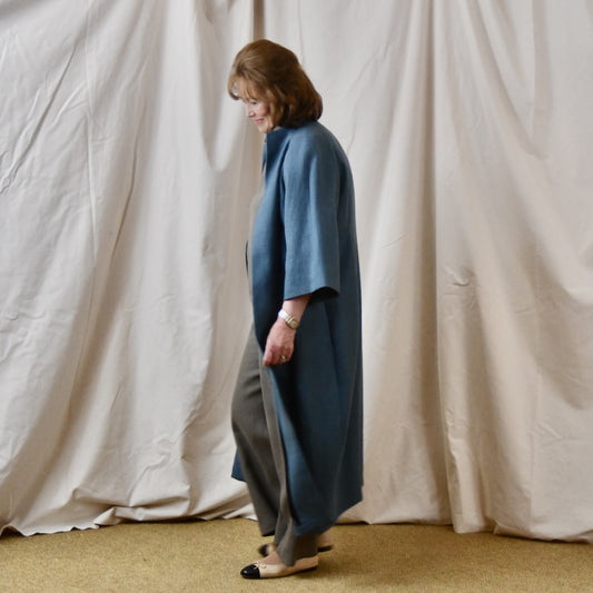 Irish Linen Cocoon Coat in mid blue. This longer length cocoon coat has tucks to front and rear, side pockets and bracelet length sleeves . Handmade in Britain. Side View.