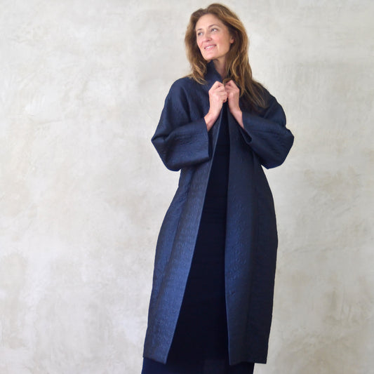Long Blue Brocade Cocoon Coat. Delicate patterning on a luxurious deep navy background. Loose fitting easy coat. Handmade in Britain. Full Shot.