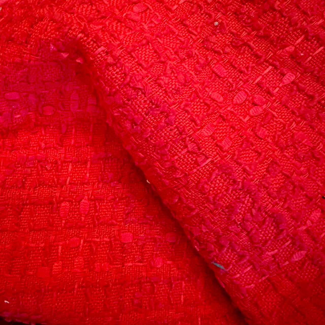 Close-up of textured red fabric on EdNerat’s Tailored Boat Neck Blouse in Linton TWeeds Boucle, highlighting a raised geometric pattern, soft material, and visible woven details with subtle color and weave variations.