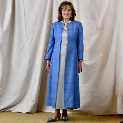 Tailored, Fitted Hourglass shaped coat in a summer-weight Silk Madras in Blue. This is a long-sleeved, calf-length blue summer coat with an hourglass shape. Shown from the side-front. A perfect summer coat for weddings and special occasions. Handmade in Britain.