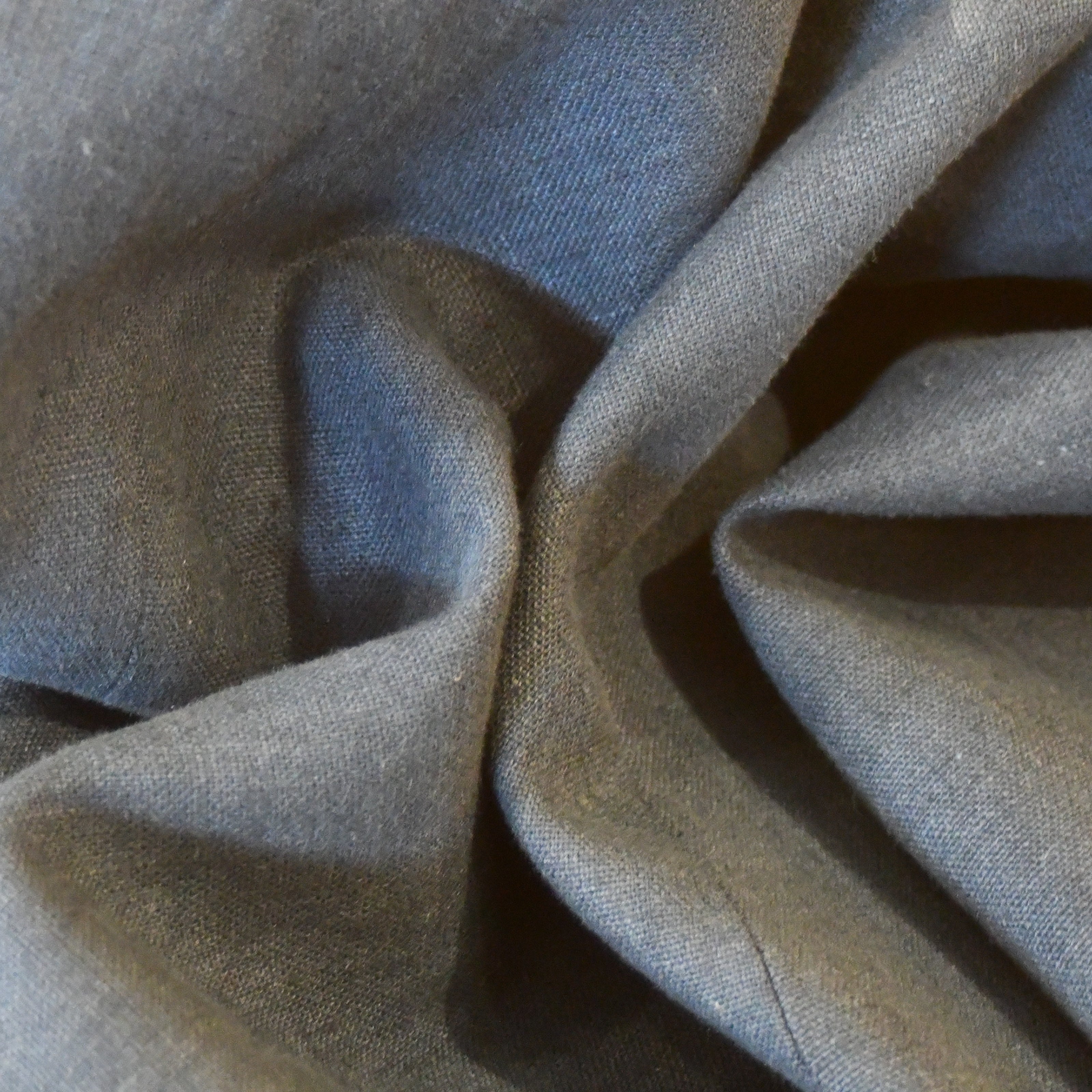 Close-up of dark gray, British-made fabric with soft folds and creases, creating an abstract, textured pattern.