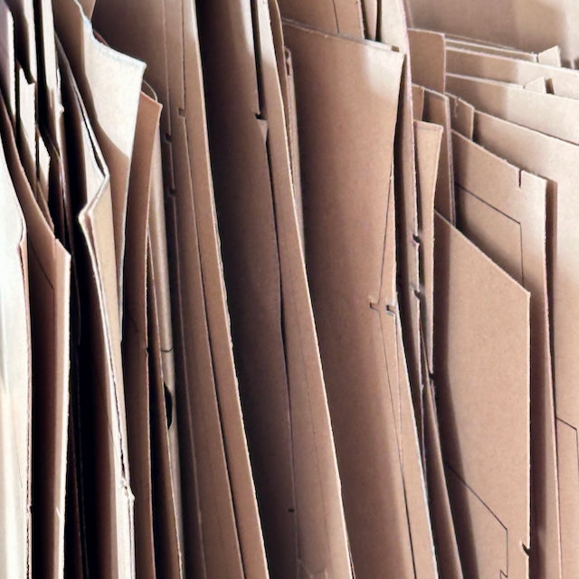 A close-up view of several bespoke file folders or cardboard dividers, hand-made and stacked vertically in an organized manner.