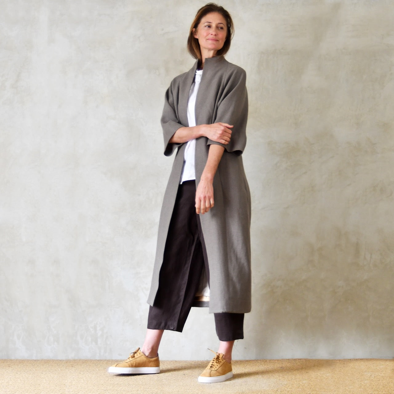 A Long Cocoon Coat in a mid-brown coloured Irish Linen. Wide Sleeves and loose, relaxed fit. The coat falls below the knees and is shown from the front. Handmade in Britain.