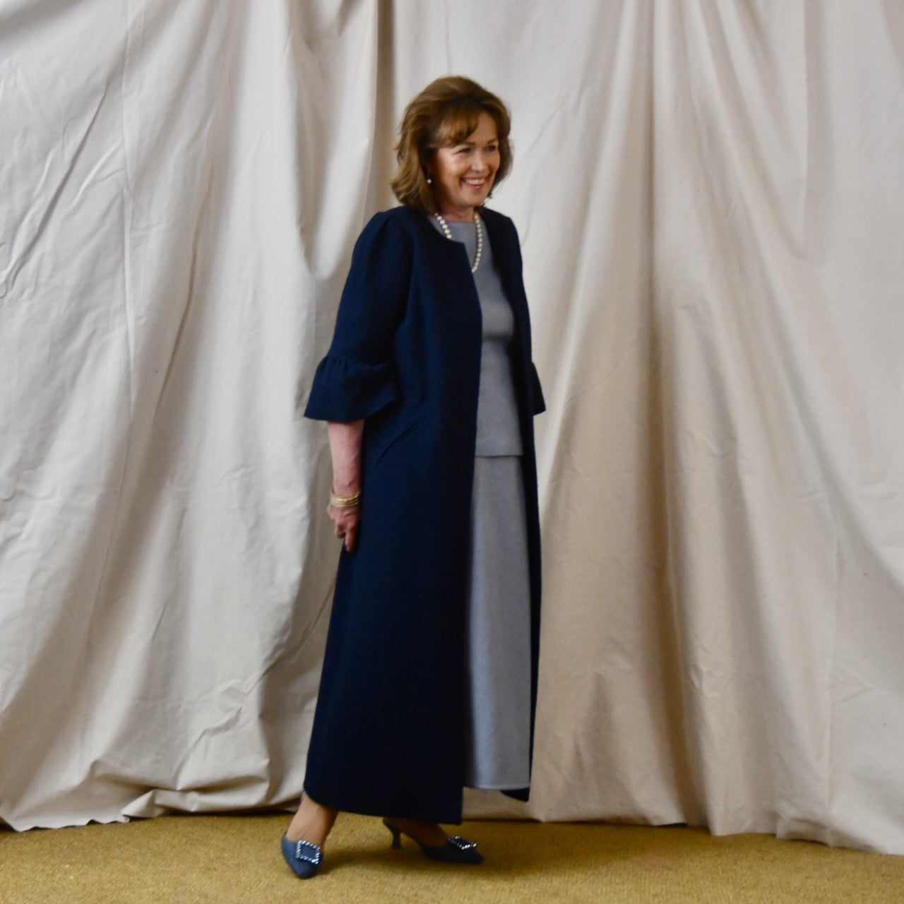 Bespoke Boucle A Line Bell Sleeve Coat. This is a Spring-summer weight coat in a navy cotton boucle from Linton Tweeds. Handmade in Britain. Walking View.