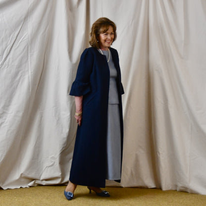 Bespoke Boucle A Line Bell Sleeve Coat. This is a Spring-summer weight coat in a navy cotton boucle from Linton Tweeds. Handmade in Britain. Walking View.