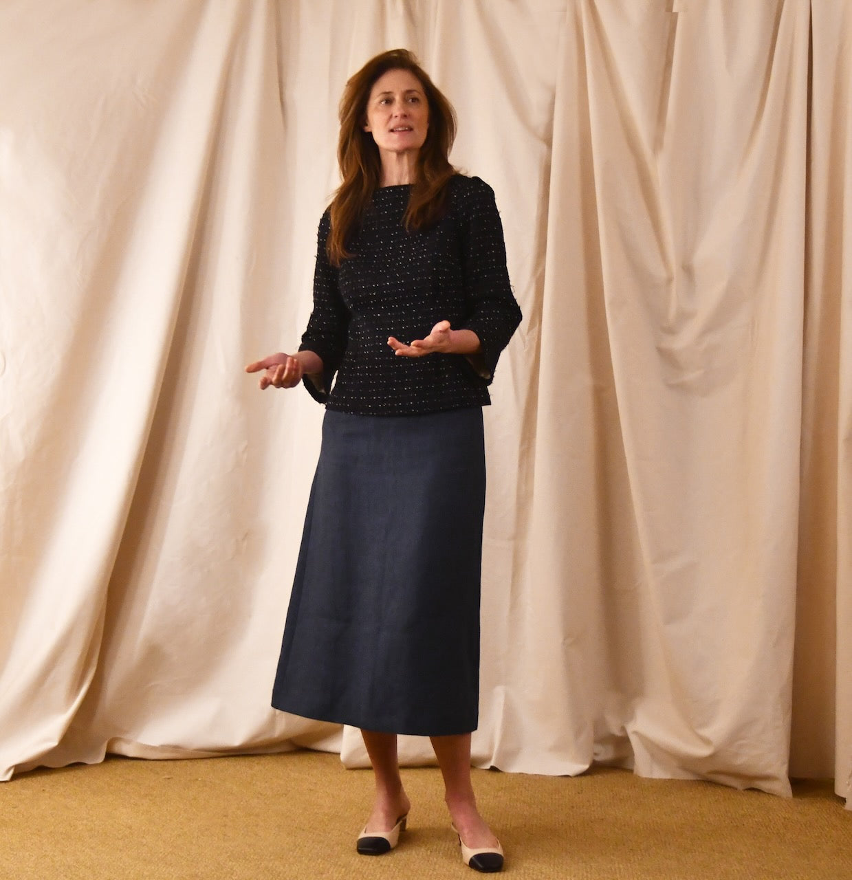 A Tailored Boat Neck Blouse in Navy Cotton Boucle, paired with a long blue skirt and black and beige flats. Linton Tweeds Fabric. Handmade in Britain. 