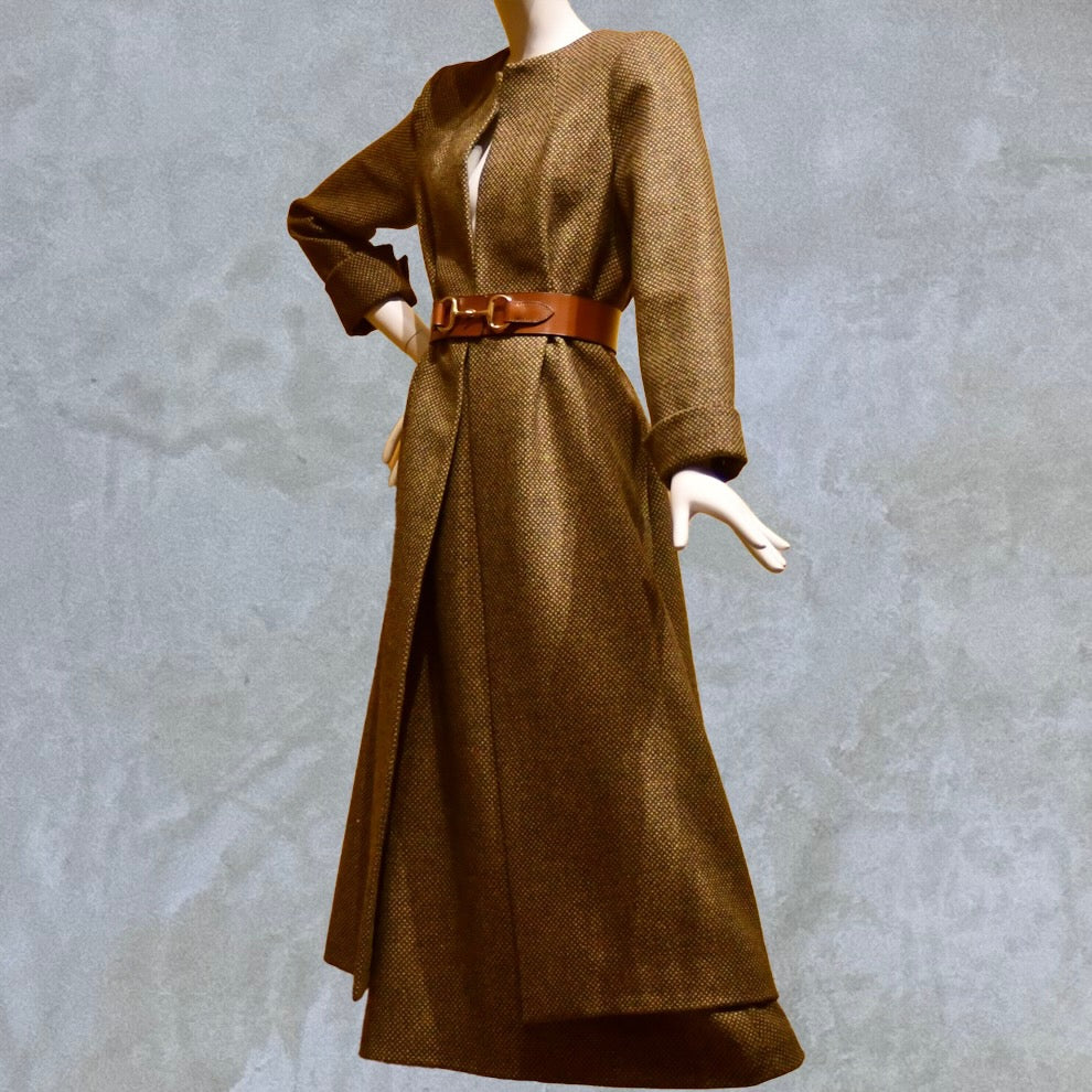 Longer length Skirted Hourglass Coat in Orange-Green Tweed. This shaped coat uses clever tailoring details to create a wonderfully flattering and easy to way skirted shape. With waist-enhancing tucks it will flatter the most testing of frames.  Belted Side View. Entirely made in Great Britain.