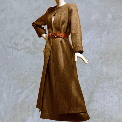 Longer length Skirted Hourglass Coat in Orange-Green Tweed. This shaped coat uses clever tailoring details to create a wonderfully flattering and easy to way skirted shape. With waist-enhancing tucks it will flatter the most testing of frames.  Belted Side View. Entirely made in Great Britain.