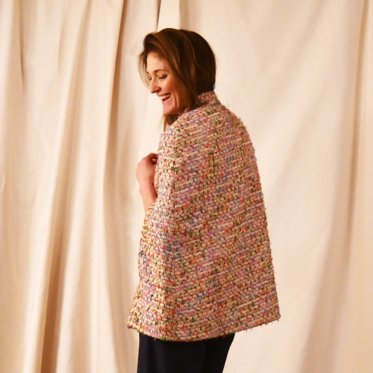 Rear View of A Vintage Style Swing Cape  in Pale Multicoloured Boucle from Linton Tweeds. Fun, young and elegant. Handmade in Britain. 