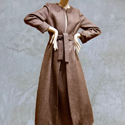 Long fitted tweed coat in pink colour. The ankle-length coat showcases a gray-pink textured tweed, hourglass tailoring, fitted seams, and back tucks. Handmade in Britain.