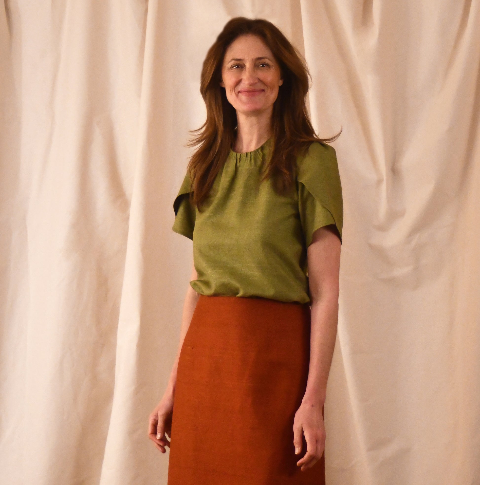 A Tulip Sleeve Blouse in lime green Silk Matka, paired with a high-waisted rust-coloured skirt. Handmade in Britain. 