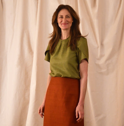 A Tulip Sleeve Blouse in lime green Silk Matka, paired with a high-waisted rust-coloured skirt. Handmade in Britain. 