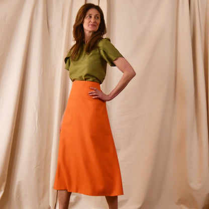 A bespoke lime green coloured Tulip Sleeve Blouse in Lime Green Silk Matka, paired with an orange midi skirt.Handmade in Britain. 