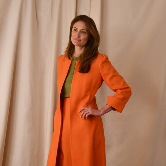 Tailored, Fitted, Hourglass Coat in Orange Silk Matka. The coat is shown worn open in an elegant and relaxed look. Handmade in Britain.