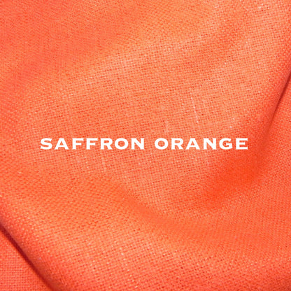 A close-up of textured fabric in a vibrant saffron orange color with the words SAFFRON ORANGE in bold white letters, showcasing British-made bespoke quality.