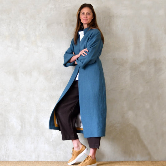 Longer Length Cocoon Coat in Blue Irish Linen. An easy to wear Spring-summer coat in a delightfully flattering cocoon shape. An investment piece to last across the years. Handmade in Britain. Side View.