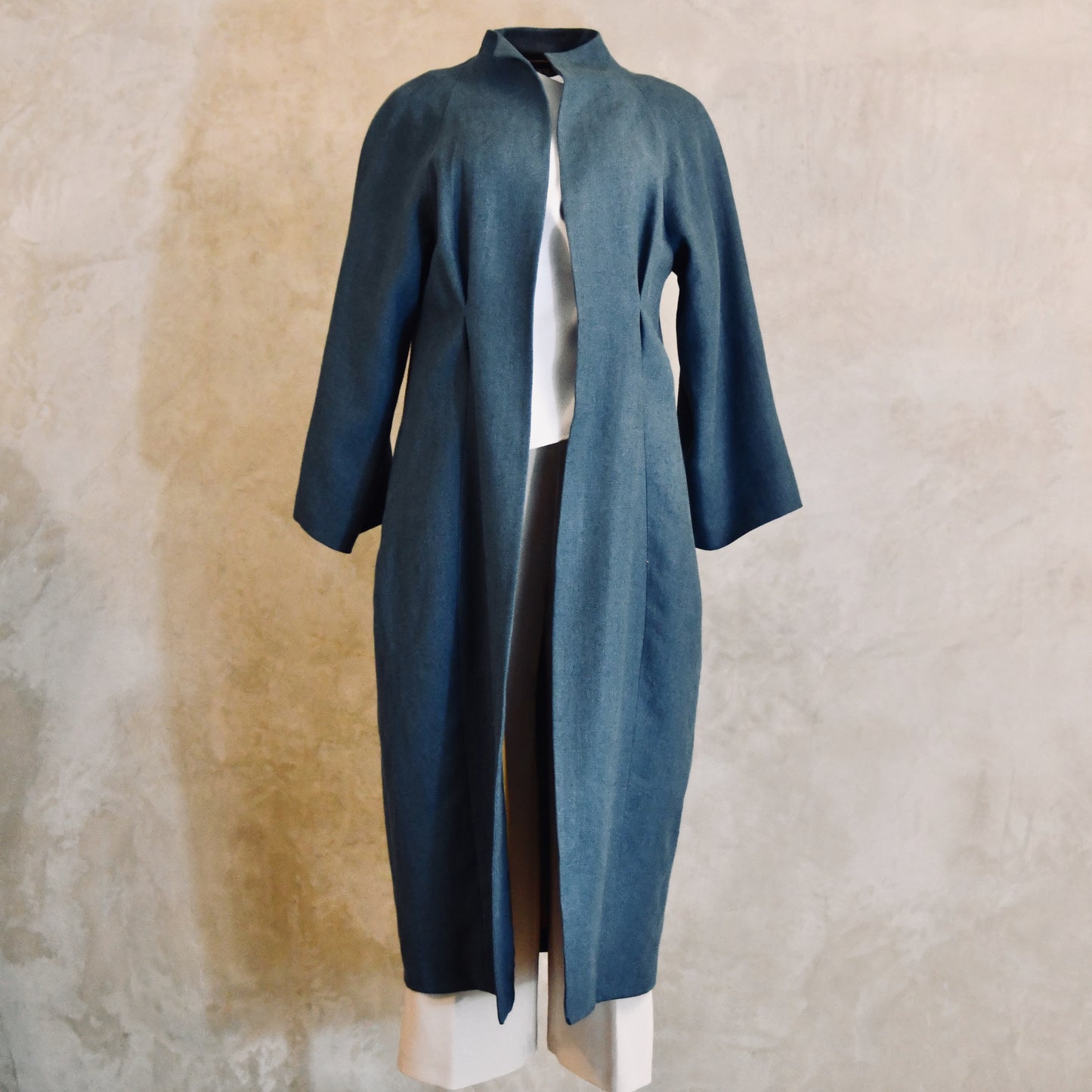 A Long Cocoon Coat in Sea-Blue Irish Linen. Wide SaLonger Length Cocoon Coat in Blue Irish Linen. An easy to wear Spring-summer coat in a delightfully flattering cocoon shape. An investment piece to last across the years. Handmade in Britain.leeves and loose, relaxed fit. The coat falls below the knees and is shown from the back. Handmade in Britain. Front View.