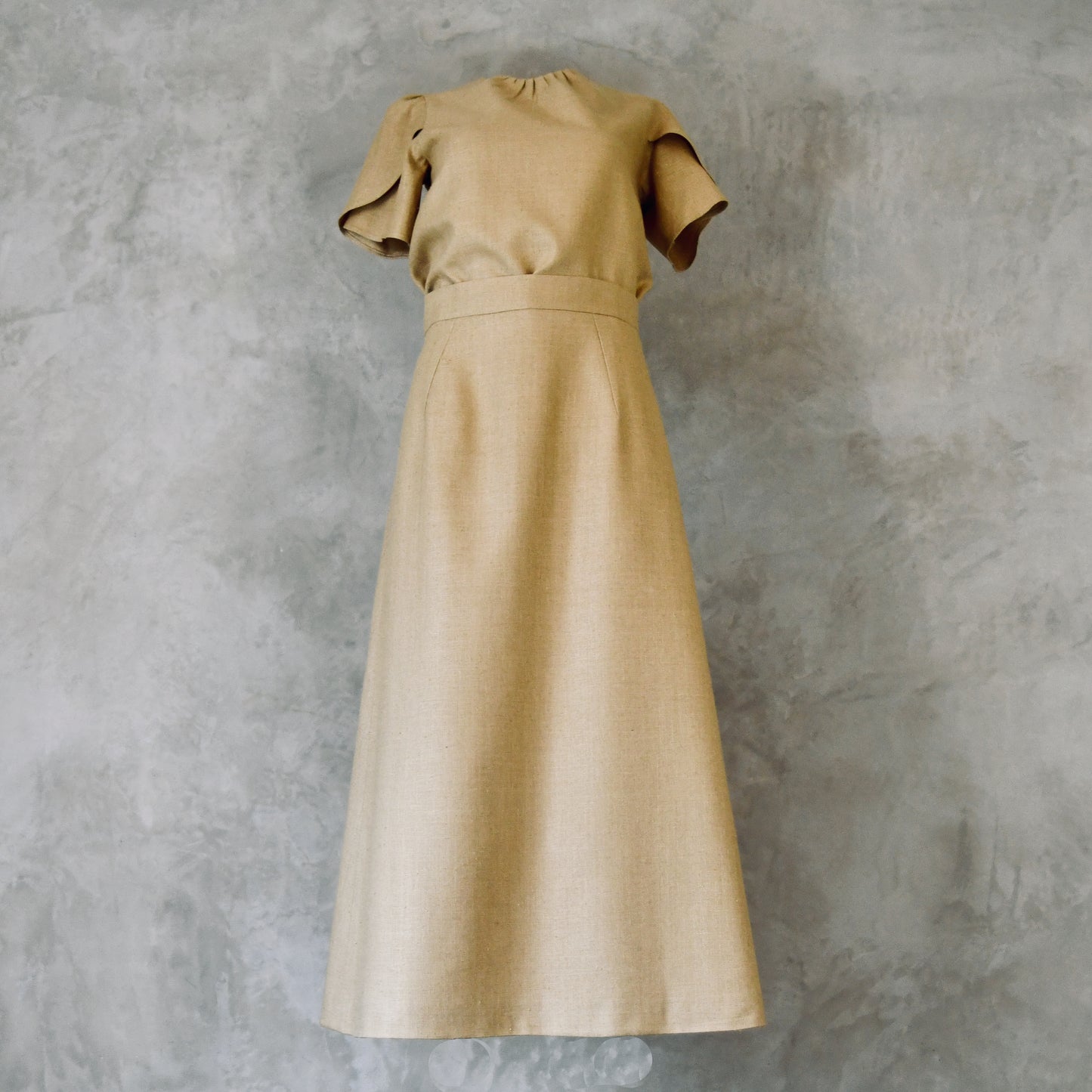 A Waisted Silk Summer A-Line Skirt in a pale coloured wheat. Featuring a fitted waist and simple, sophisticated design with an elegant drape, highlighting its simple and refined design. Handmade in Britain. Shown with a matching Tulip-Sleeved Blouse. 