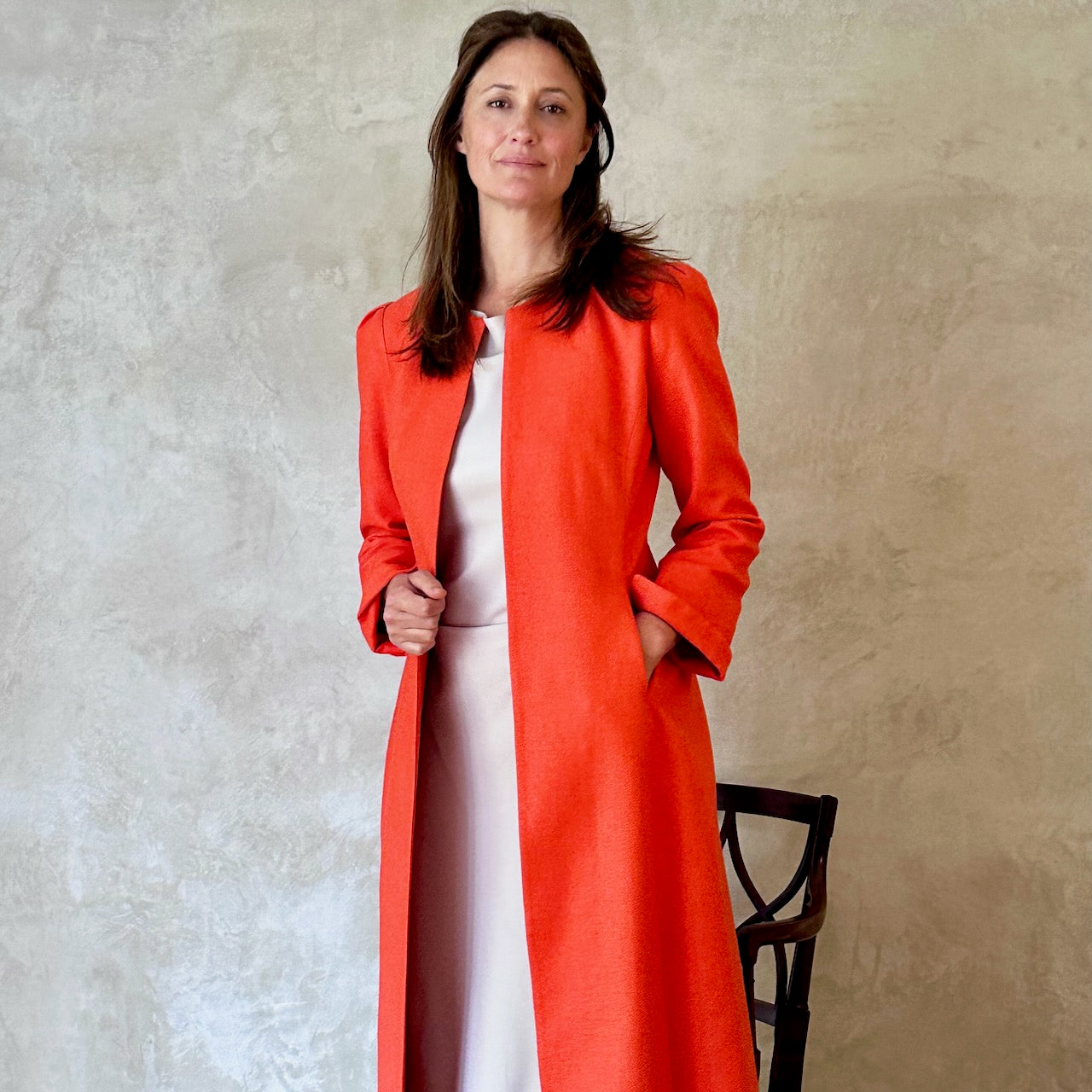 SiaTailored, Fitted, Hourglass Coat in Orange Silk Matka. The coat is shown worn open in an elegant and relaxed look. Handmade in Britain. 