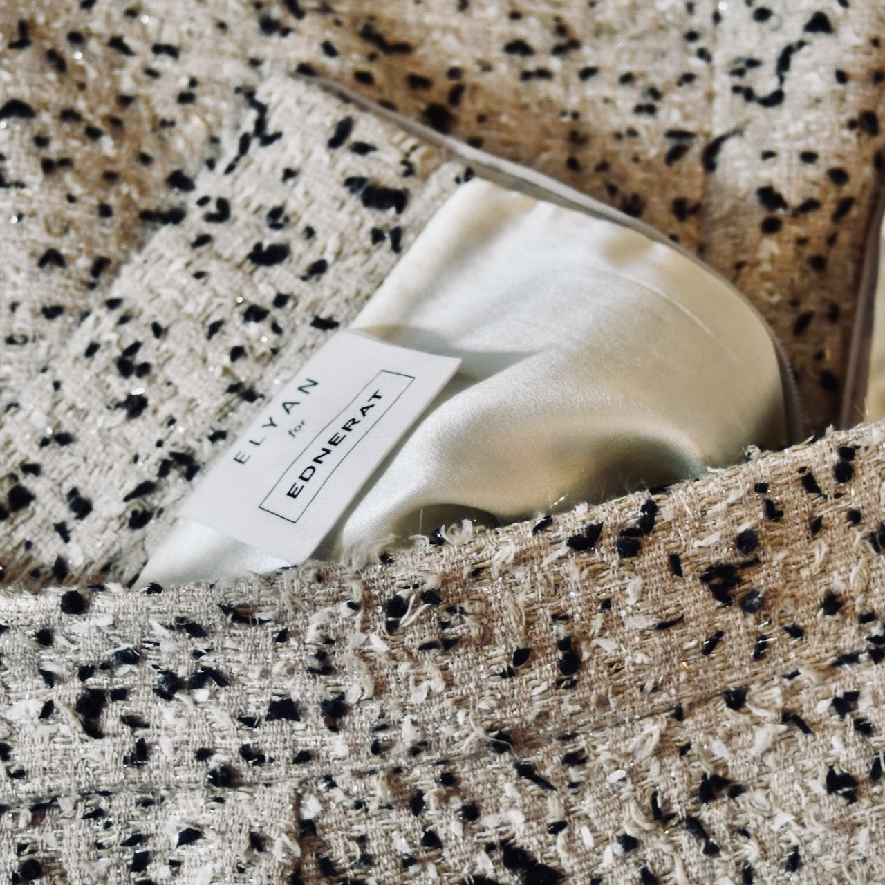 Bespoke Tailored Hourglass-Shaped Coat in Camel, Black and White Flag Textured Bouclé, from Linton Tweeds. A Collar-less shaped coat for weddings and formal occasions. Handmade in Britain. Skirt Detail.
