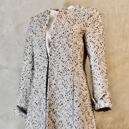 Tailored, Fitted, Hourglass Coat in camel, black, and white Flag Textured Bouclé from Linton Tweeds. Handmade in Britain, the edge-to-edge coat features full length sleeves and a collarless neckline. Handmade in Britain.