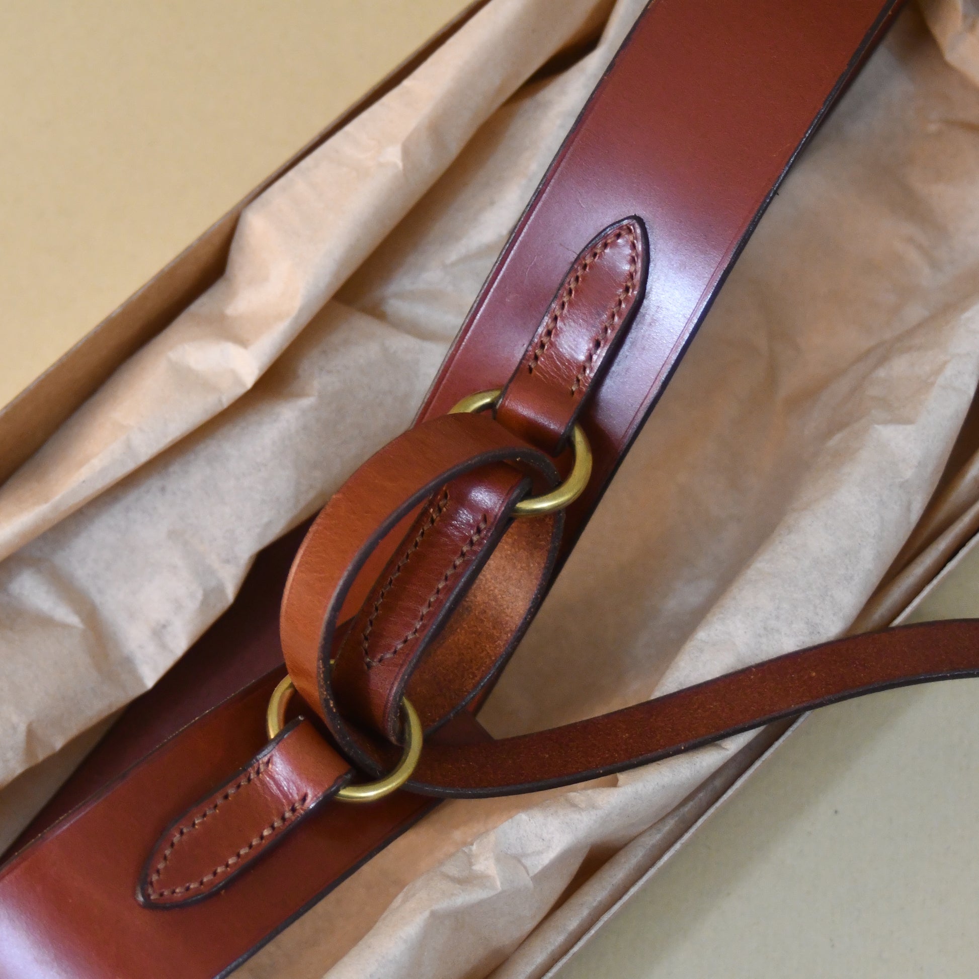 A Boxed saddle Leather Belt.  A close-up of the EDNERAT Hazel Ring Wrap Belt - 68cm, crafted from British saddle leather with solid brass fittings. Handmade in Britain.