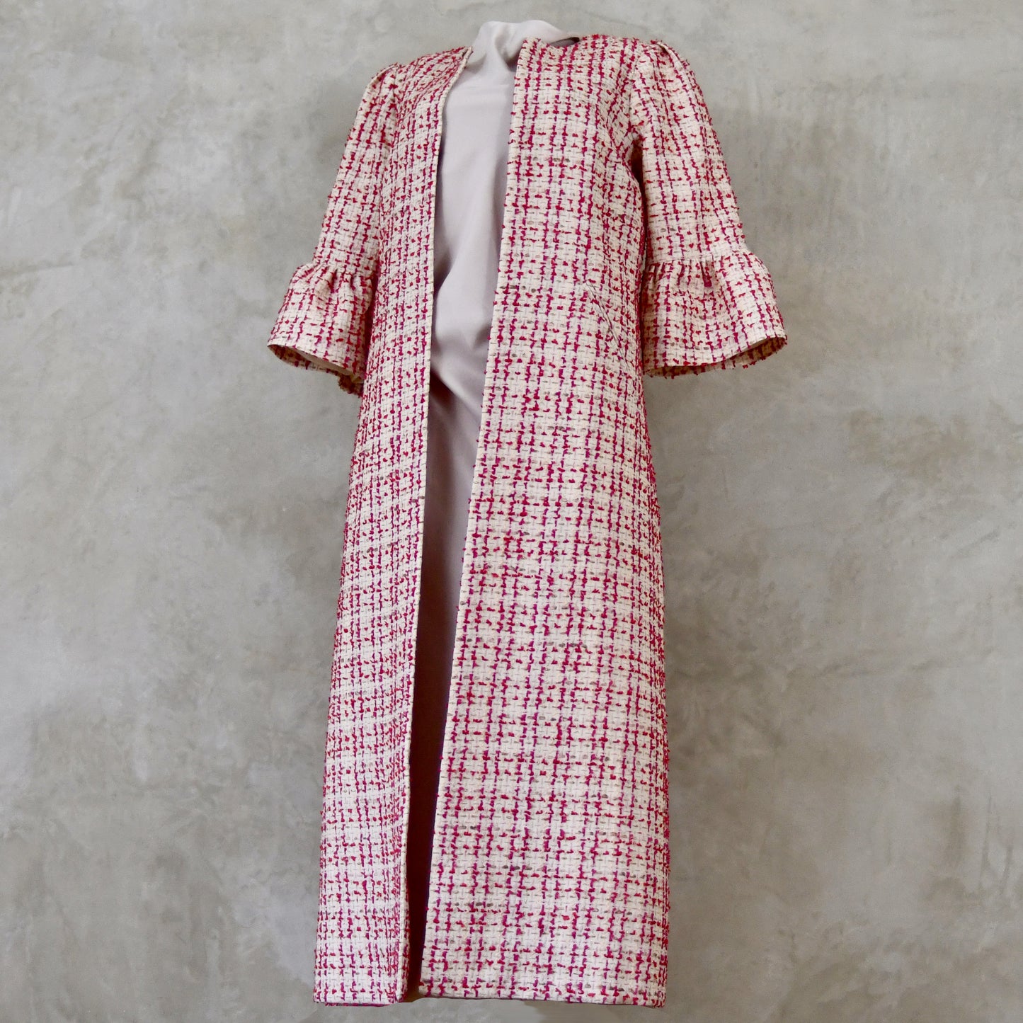 Bell Sleeve A-Line Coat in Pink Patterned Linton Tweeds Boucle. A pretty, longer length A-line coat in a pink, cream and gold check pattern for smart spring and summer occasions. Entirely made in Great Britain. Side On View.