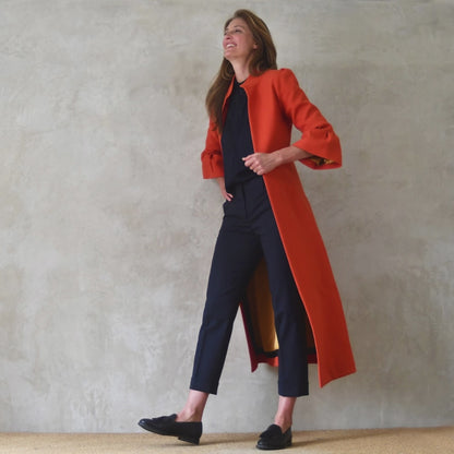 Bespoke Bell Sleeve A-Line Coat in Orange Wool Crepe. This is an elegant longer length A-Line coat in a stupendous burnt orange wool crepe from Yorkshire. With a magnificent drape and delicate sleeve detailing, this coat will take you everywhere. Entirely made in Great Britain.